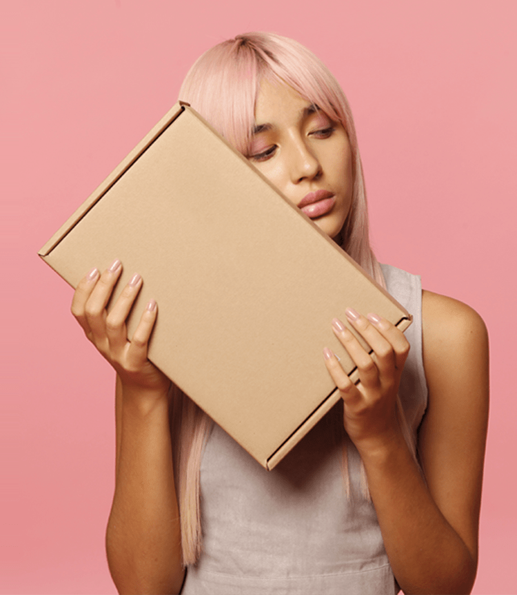 A pink-haired girl holds the Restora Treatment Set. It contains the Restora Protein Shampoo, Restora Protein Treatment and Restora Protein Conditioner.